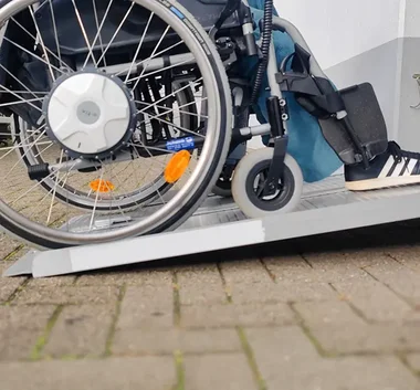 Ansicht Rollstuhlrampe mit Rollstuhlfahrer der darüber fährt 