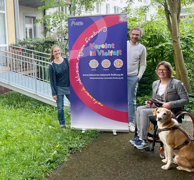 Foto von Vereinsmitgliedern neben Banner stehend 