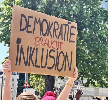 Schild mit Spruch: "DEMOKRATIE BRAUCHT INKLUSION" 