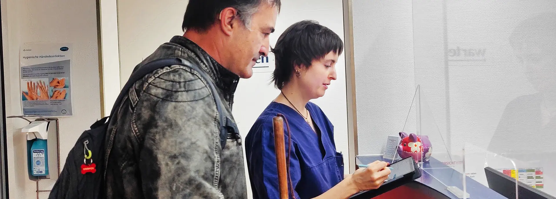 Sehbehinderte Person füllt Formular mit Arzthelferin aus