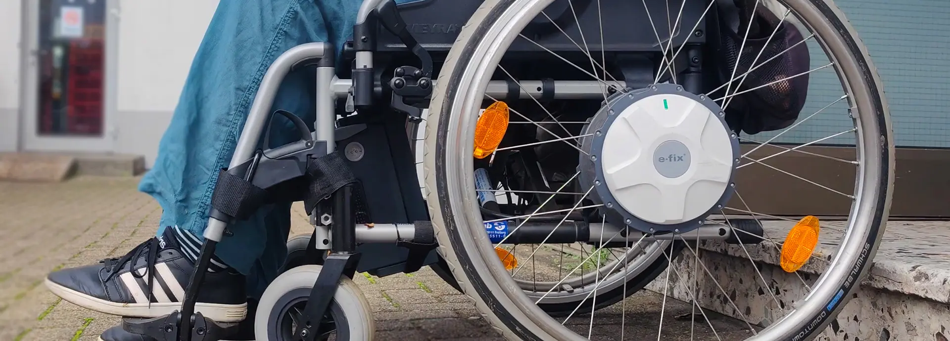 Personen mit Rollifahrer in der Mitte jubeln zur Sonne